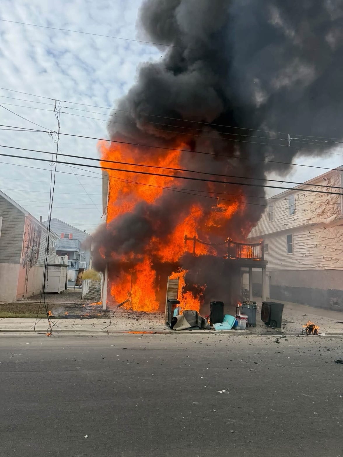 Flames and black smoke pour from a raised house on a West Wildwood street